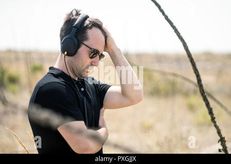 Jungen attraktiven Mann mit Sonnenbrille hören die Musik auf seine Kopfhörer Stockfoto