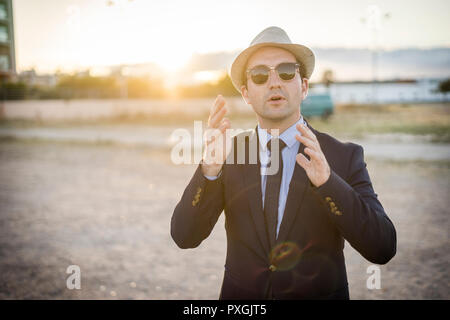 Lifestyle Portrait von Vintage suchen junger Mann in Anzug und Sonnenbrille bei Sonnenuntergang Stockfoto