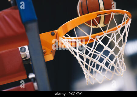 Basketball scoring Warenkorb beim Sport Arena. Riefen die gewinnenden Punkte an einem Basketballspiel. Die orange Basketball Ball fliegt durch den Korb Stockfoto