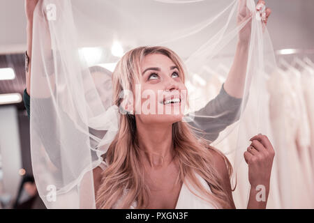 Blonde Frau an ihrem Schleier suchen begeistert Stockfoto