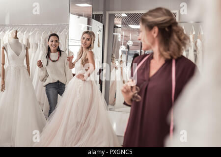 Freudige junge Frauen, die auf der Hochzeit Kleid designer Stockfoto