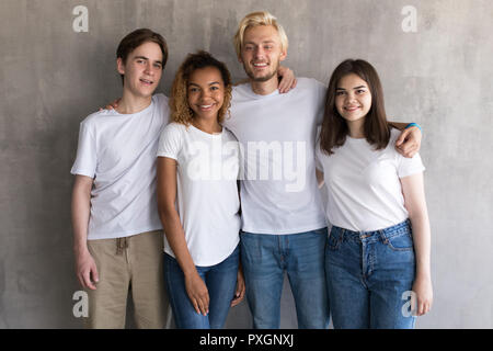 Multiethnische Gruppe von Freunden in den weißen T-Shirts auf grauem Hintergrund. Stockfoto
