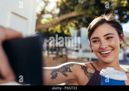 Weibliche im freien Kaffee und vlogging mit Ihrem Smart Phone. Social media Einfluss ihrer Aktivitäten Aufzeichnung als Inhalt für Vlog. Unter selfi Stockfoto