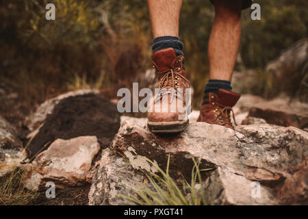 Nahaufnahme der männlichen Wanderer Schuhe auf Rocky Trail. Man Walking durch robusten Pfad tragen trekking Stiefel. Stockfoto