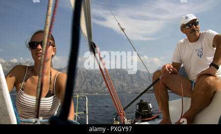 Montenegro, September 2018 - eine junge Frau und Skipper in einem Segelboot cockpit Segeln in der Bucht von Kotor Stockfoto