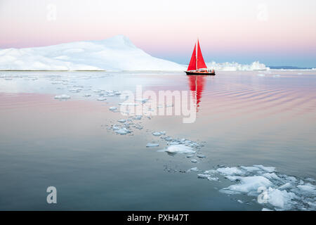 Kleine rote Segelboot Kreuzfahrt unter schwimmende Eisberge in der Diskobucht Gletscher mitternachtssonne Saison von polaren Sommer. Ilulissat, Grönland. Stockfoto