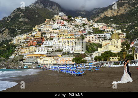 Braut und Bräutigam zu Fuß auf den Strand mit dem Hintergrund der bunten Häuser in Positano, einem Dorf hochliegend auf der südlichen Italien Amalfi Küste Stockfoto