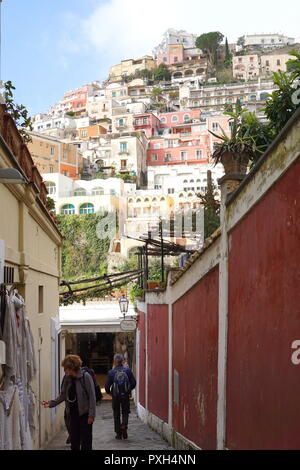 Touristen zu Fuß auf einer engen Straße mit dem Hintergrund der bunten Häuser in Positano, einem Dorf hochliegend auf der südlichen Italien Amalfi Küste Stockfoto