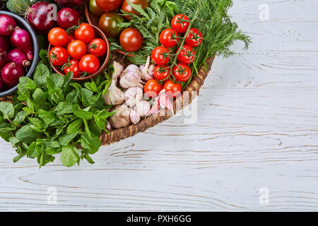 Gemüse sortiert in einem großen Korb auf einem weißen Schreibtisch Stockfoto