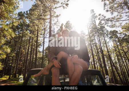 Junges Paar in relationshiop sitzen auf dem Dach in der Mitte eines hohen Pinien Wald in Berg. Liebe und Freiheit für tausendjährigen Menschen in Stockfoto