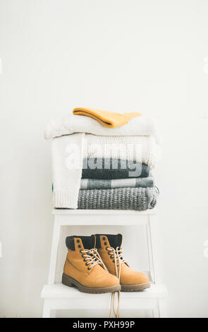 Stapel der warme Pullover und Decken, Kappe und Stiefel Stockfoto