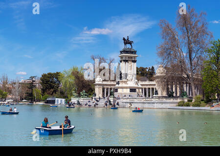 Madrid, El Retiro. Paar Bootfahren auf dem estanque Grande del Retiro mit der Alfonso XII Denkmal hinter, Parque del Buen Retiro, Madrid, Spanien. Stockfoto