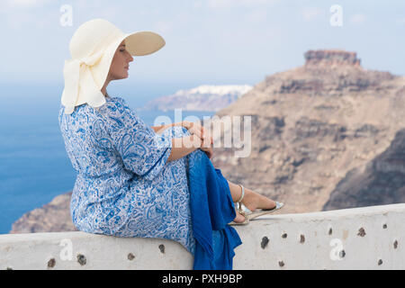Junge Frau in einem weißen und blauen Kleid genießt einen Spaziergang rund um Santorini Stockfoto