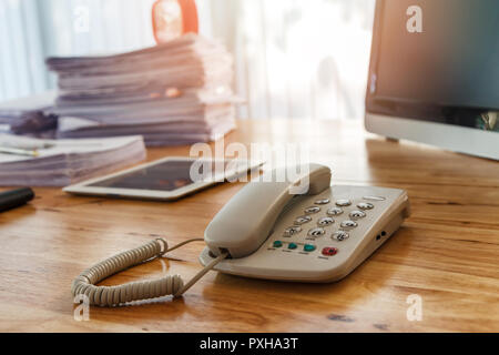 Telefon und Büromaterial auf Büro Schreibtisch. Holztisch mit Büromaterial im Home Office am Morgen Stockfoto