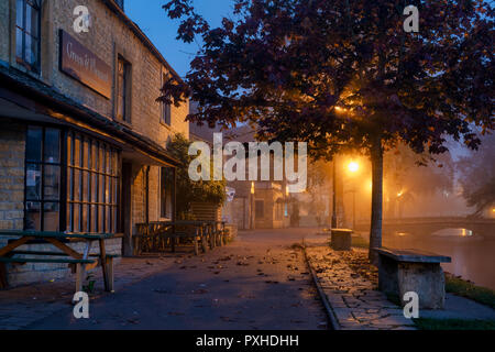 Dunst und Nebel im Morgengrauen in der cotswold Dorf Bourton auf dem Wasser im Herbst. Bourton auf dem Wasser, Cotswolds, Gloucestershire, England Stockfoto