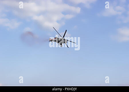 Kampfhubschrauber auf blauer Himmel mit weißen Wolken. Ansicht von unten. Stockfoto