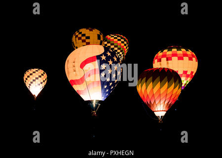 Bunt leuchtende Heißluftballons fliegen in der Nacht vor einem schwarzen Hintergrund der Nachthimmel Stockfoto