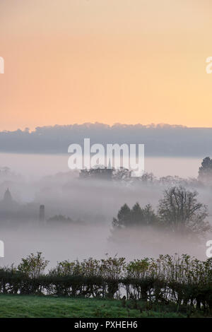 Dunst und Nebel bei Sonnenaufgang rollen über die Landschaft rund um den cotswold Dorf Lower Slaughter im Herbst. Cotswolds, Gloucestershire, England Stockfoto