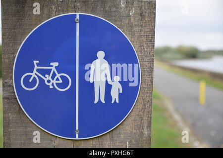 Rundschreiben gemeinsames Radfahren und Wandern Schild mit weißer Schrift auf blauem Hintergrund auf einem hölzernen Pfosten mit Pfad Straße im Hintergrund Stockfoto