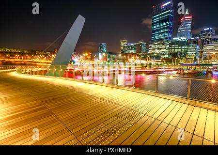 Holzsteg von Elizabeth Quay Fußgängerbrücke durch die Nacht in Elizabeth Quay Marina, eine neue touristische Attraktion in Perth, Western Australia beleuchtet. Esplanade auf den Hintergrund. Nacht Szene. Stockfoto