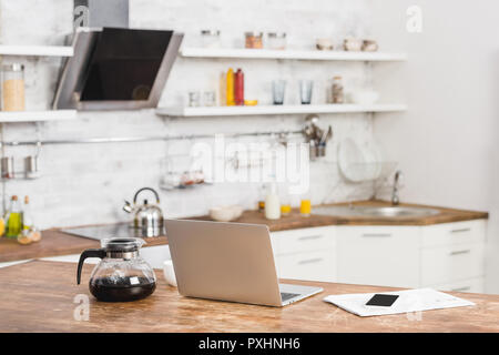 Laptop, Smartphone und Kaffee Topf auf den Küchentisch Stockfoto