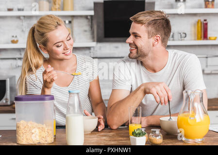 Lächelndes Paar essen Cornflakes mit Milch auf das Frühstück in der Küche Stockfoto