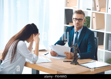 Anwalt, Papiere und die Kamera während der traurigen Frau Client im Büro Stockfoto