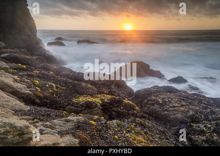 Die zerklüftete Küstenlinie Sonnenuntergang über Gray Whale Cove State Beach. Stockfoto