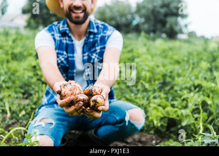 Zugeschnittenes Bild von Bauer anzeigen reif Kartoffeln in die Hände im Feld Stockfoto