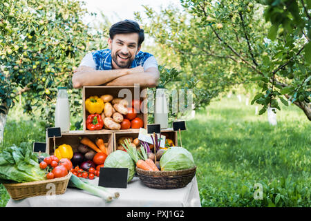Stattliche Bauern lehnen auf Kisten mit Gemüse am Bauernmarkt Stockfoto