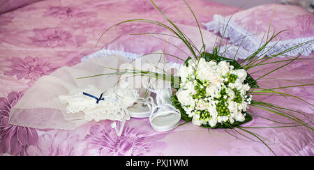 Brautstrauß mit Schuhen und Strumpfband auf der Wisteria Bett. Stockfoto