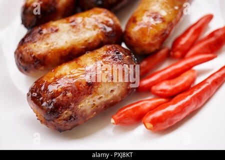 Close-up I-SAN Wurst oder Wurst aus Schweinefleisch vom Grill mit roten Chilis auf weiße Platte. Traditionelle thailändische Essen. Stockfoto