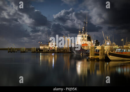 Schiffe im Hafen von West-Terschelling, eine Insel im Wattenmeer der Niederlande. In dieser langen Belichtungszeit Nachtszenen, die rotierenden Strahl eines lig Stockfoto