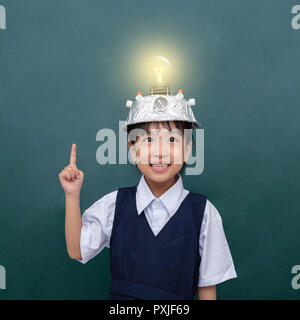 Asiatische chinesische Mädchen tragen Virtuelle Realität Helm und Zeigefinger bis zu Glühbirne gegen grüne Tafel Stockfoto