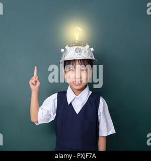 Asiatische chinesische Mädchen tragen Virtuelle Realität Helm und Zeigefinger bis zu Glühbirne gegen grüne Tafel Stockfoto