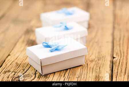 Handgearbeitete Geschenkboxen mit blauen und roten Band und Bogen auf dem Holz alte Tabelle Stockfoto