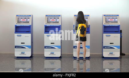 China Wuhan Tianhe - September 10, 2018: Die junge Frau mit dem Check-in-Automaten am Flughafen erhalten der Bordkarte. Stockfoto