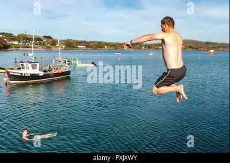 Schull, West Cork, Irland. 23 Okt, 2018. Clinton Copithorne von Ballydehob macht die meisten der ungewöhnlich warmen Wetter durch einen Sprung ins Meer aus Schull Pier. Sunshine hat die Reihenfolge der Tag heute mit Höhen von 13-15° Celsius in West Cork. Credit: Andy Gibson/Alamy Leben Nachrichten. Stockfoto