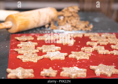 Sternförmige zimt Weihnachtsplätzchen sind bereit für den Ofen und im Hintergrund ist der Plätzchenteig und einem Teig rollen. Stockfoto