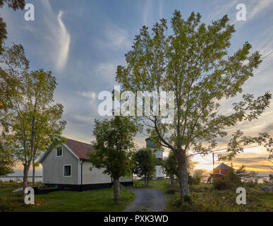 Blick auf einen Leuchtturm, Haus und Baum gegen einen schönen Sonnenuntergang Abendhimmel mit weichen gering bewoelkt Gräsö, Schweden Stockfoto