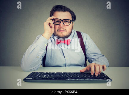 Nach chunky Mann mit Tastatur und halb geschlossenen Augen mit Sehstörungen auf grauem Hintergrund Stockfoto