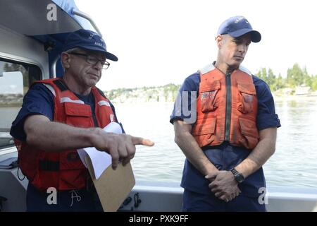 Kapitän Sean Kreuz (rechts), Leiter der Reaktion, Coast Guard 13. Bezirk, hört wie Kent Brown, ein coxwain mit Coast Guard Auxiliary Bezirk 13, Flottille 1-2, führt eine Sicherheit kurz vor der Abfahrt von der Naval Kraftstoff Deportieren in Manchester, Washington, 6. Juni 2017. Die Beamten der Küstenwache und der Army Corp der Ingenieure beobachtet eine gemeinsame spill Übung aus einem Blake Insel aus der braunen Gefäß. Stockfoto