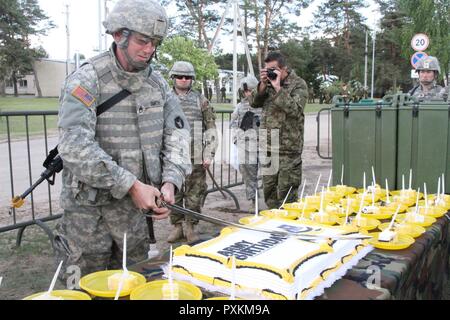 SSG Klee Smith schneidet einen Kuchen zu Ehren der US-Armee 242nd Geburtstag Juni 14, 2017 in Pabrade, Litauen. Kroatisch, Niederländisch, Norwegisch, Litauisch, Deutsch, Portugiesisch und Army National Guard Kräfte aus Pennsylvania und Minnesota schlossen sich ihnen auch während der Feier während der Übung Iron Wolf 17. Stockfoto