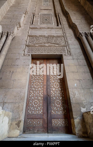 Externe Stil der alten Steine Steinwand mit Arabesque dekoriert Holztür von Stein gerahmt verzierten zylindrische Lichtmasten, die zu Al Rifai Moschee, O Stockfoto