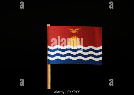 Eine offizielle Flagge Kiribati auf Holzstab auf schwarzem Hintergrund. Staat im Nahen Ozeanien, Pazifik. Segeln Sonne auf Meer. Stockfoto