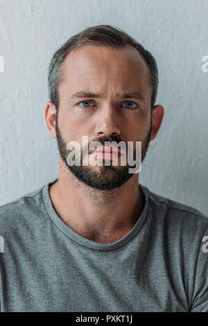 Close-up Portrait von frustriert bärtigen Mann an der Kamera schaut auf Grau Stockfoto