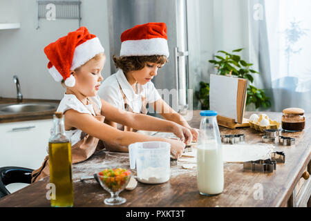Adorable Kinder in santa Hüte Vorbereitung Weihnachtsplätzchen zusammen Stockfoto