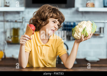 Unglückliche kind Holding süßen Eis und gesunde Blumenkohl Stockfoto