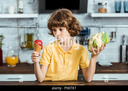 Junge Holding süßen Eis und gesunde Blumenkohl Stockfoto
