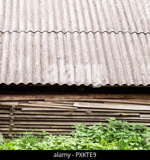 Alten hölzernen Planken unter dem Dach der alten Schuppen gestapelt Stockfoto